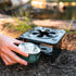 Coghlan's folding stove heating a camp mug outdoors