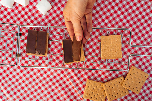 Three s'mores in a Coghlan's grill on a picnic table