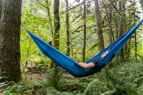 Coghlan's blue parachute hammock hung between trees at camp