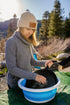 Camper washing up in a Coghlan's collapsible sink at a mountain campsite