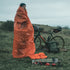 Cyclist wrapped in the Lifesystems Survival Bag beside a bike