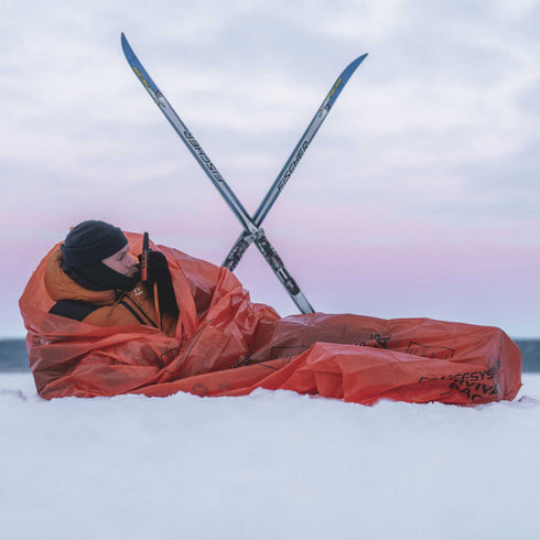 Lifesystems Survival Bag pitched between trekking poles in snow