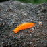Lifesystems Echo Whistle, orange, lying on a gravel path