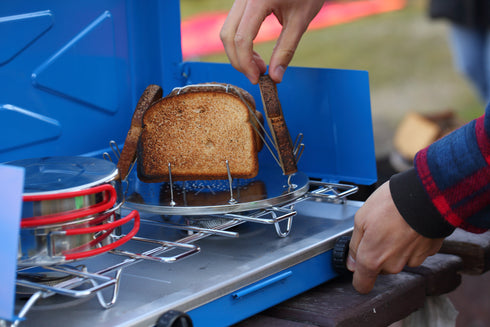 Bread toasting on a Coghlan's camp stove toaster over a gas stove