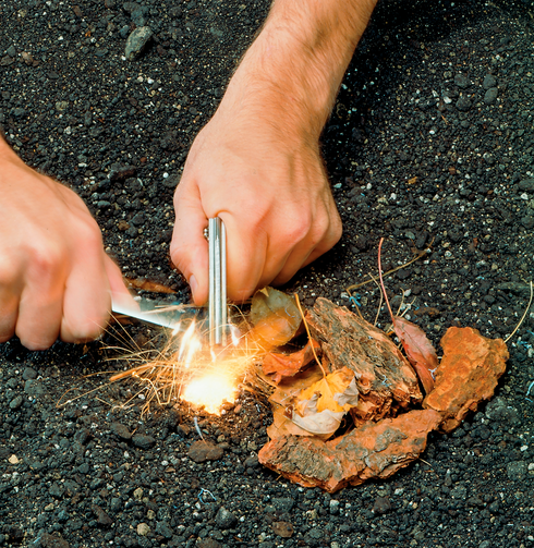 Camper lighting kindling with a Coghlan's magnesium fire starter