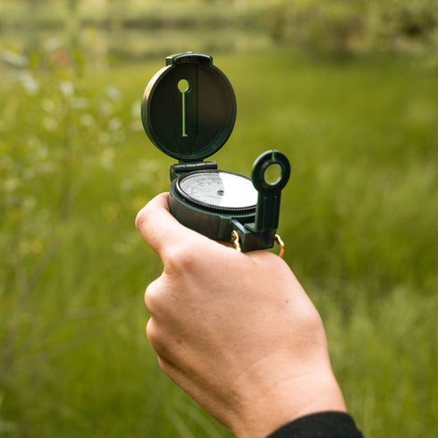 Hiker taking a bearing with a Coghlan's lensatic compass