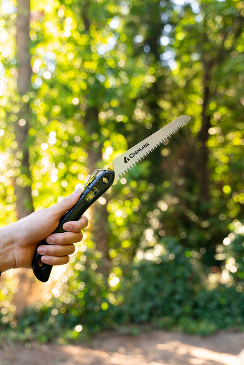 Camper holding a Coghlan's sierra saw in a forest