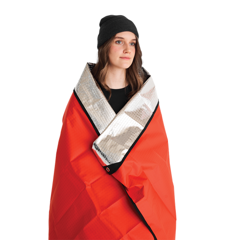 Person wrapped in a Coghlan's red and silver thermal blanket
