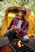 Camper roasting sausages over a fire with a Coghlan's camp fork