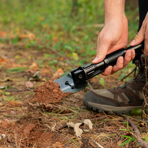 Camper digging with a Coghlan's mini shovel with pick
