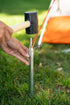 Camper driving a steel tent stake into the ground at a campsite